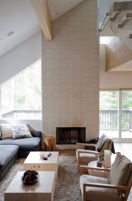 Cozy living room with a large tiled fireplace, white walls, and modern wood furniture.