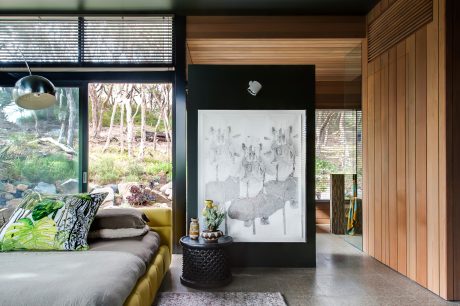 A modernist living room with wooden paneling, large windows, and abstract artwork.
