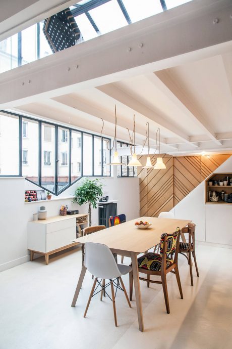 Modern dining room with wooden ceiling beams, floor-to-ceiling windows, and eclectic decor.