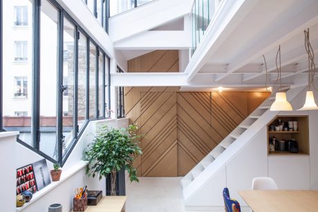 Spacious, modern interior with wooden accents, glass walls, and a stylish staircase.