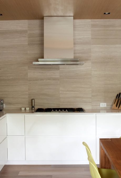 The image depicts a modern kitchen with a sleek, minimalist design. The kitchen features a stainless steel range hood and patterned tile backsplash, creating a visually appealing and functional space.