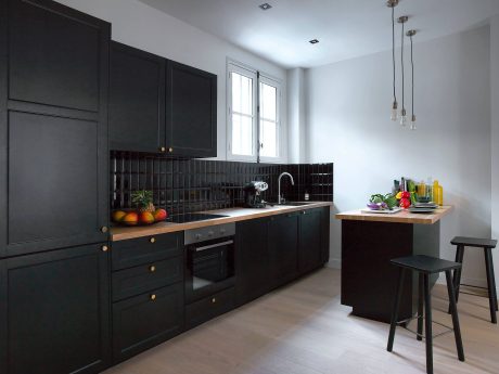 Sleek, modern kitchen with black cabinetry, wooden countertops, and pendant lighting.