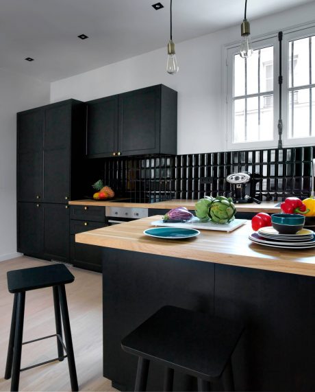 Modern kitchen with sleek black cabinets, wooden countertops, and colorful accents.