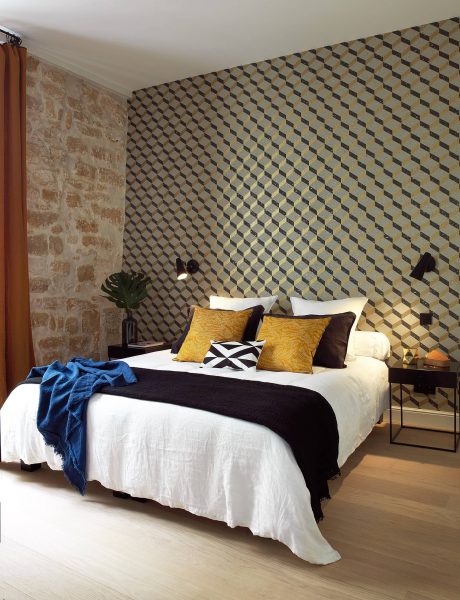 This bedroom features a unique geometric wallpaper pattern, complemented by black and white bedding and accents.