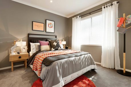 Cozy bedroom with gray walls, wooden furniture, and pops of color in textiles and decor.