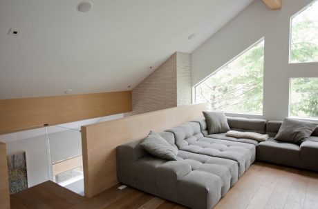 Spacious modern living room with large sectional sofa, wooden accents, and floor-to-ceiling windows.