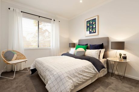 Spacious bedroom with large window, upholstered headboard, and stylish furniture.