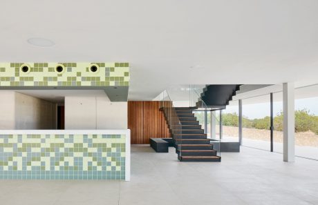 Minimalist interior with geometric tile patterns, an open staircase, and panoramic windows.