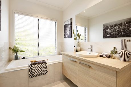 A modern bathroom with a wooden vanity, vessel sink, and large window overlooking greenery.