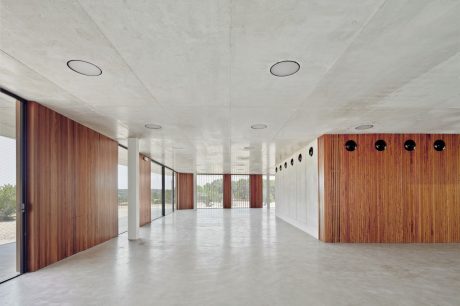 Expansive interior space with concrete floor, wood paneling, and recessed ceiling lighting.