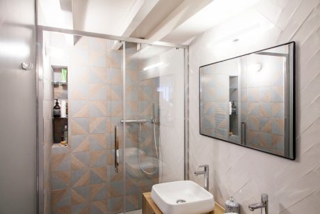 A modern, minimalist bathroom with geometric tile patterns and a sleek shower enclosure.