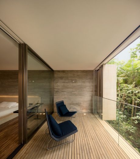 Spacious modern room with wooden walls, floor, and glass doors overlooking lush greenery.