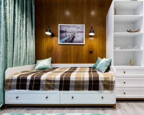 Cozy bedroom with wooden paneled walls, built-in shelving, and a plaid bedspread.
