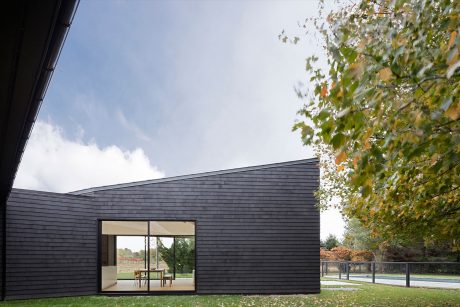 Modern, minimalist exterior with large windows overlooking a grassy landscape.