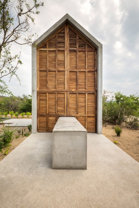 A striking architectural structure with a wooden facade and a concrete pedestal, nestled among lush greenery.
