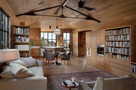 Cozy cabin interior with wood-paneled ceiling, built-in bookshelves, and rustic decor.