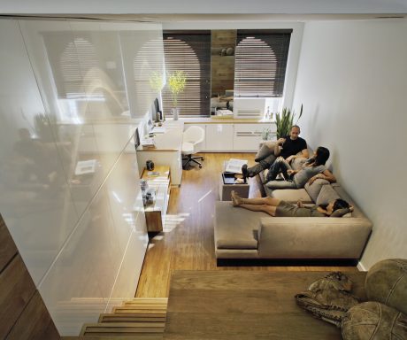 Open-concept living space with minimalist furnishings, large windows, and wooden flooring.