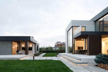 Modern architectural design with clean lines, glass panels, and landscaped outdoor space.
