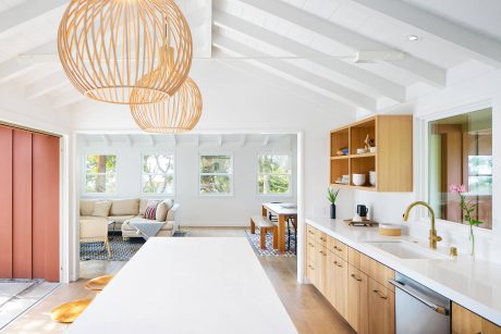 Spacious open-concept kitchen with natural wood cabinetry, pendant lighting, and views of living area.