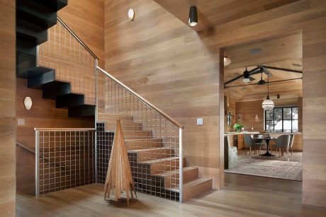 Modern open-concept home with wooden walls, metal staircase, and minimalist decor.