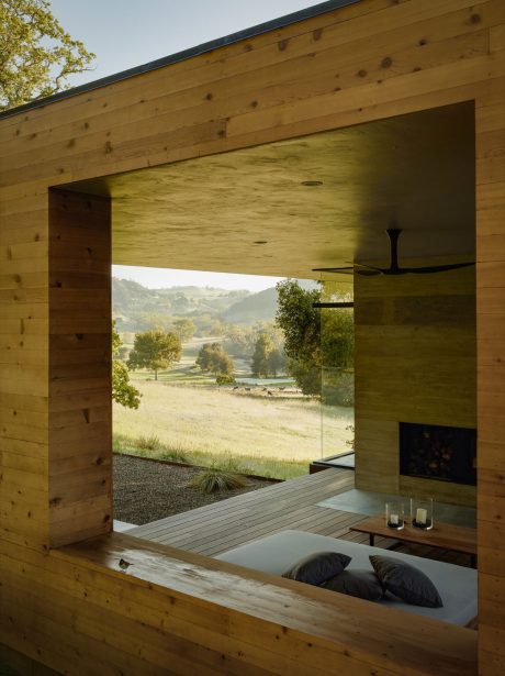Cozy wooden cabin with expansive glass doors overlooking a scenic countryside.