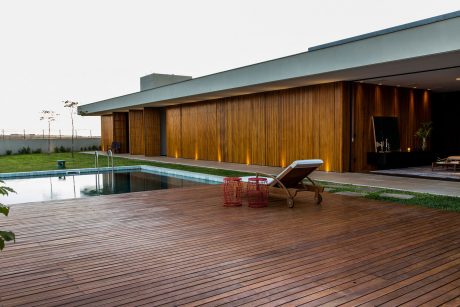 Sleek modern home with wood siding, pool, and lounge chairs on wooden deck.