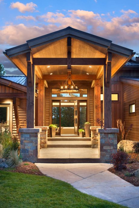 Warm wood tones, stone accents, and a covered porch welcome visitors to this rustic-style home.