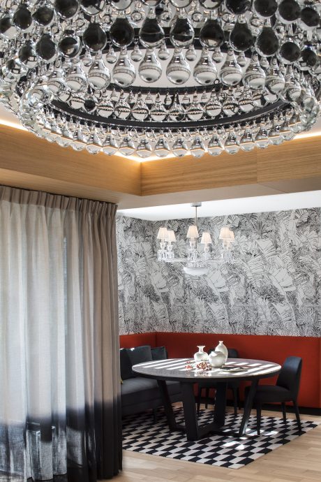 Lavish chandelier with intricate crystal design adorns the modern dining room.