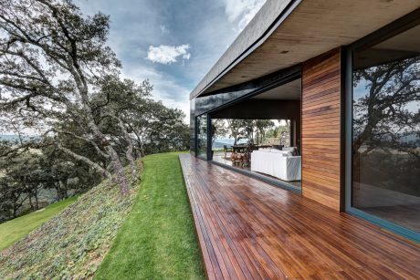 A modern, elevated home with a spacious balcony and panoramic views of the surrounding landscape.
