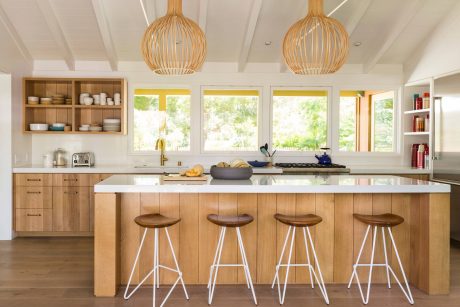 Modern kitchen with wooden cabinetry, pendant lights, and breakfast bar stools.