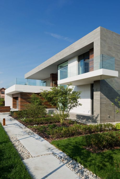 A sleek, contemporary home with geometric forms, glass walls, and lush landscaping.