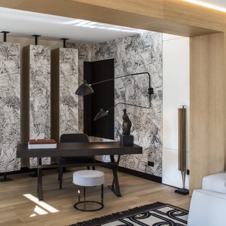 Well-designed home office with tropical-themed wallpaper, modern black desk, and sleek lighting.