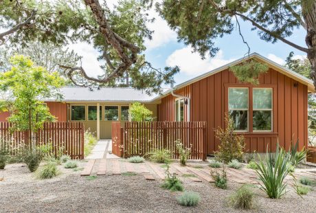 A rustic wooden cabin with a picturesque landscaped yard and surrounding trees.
