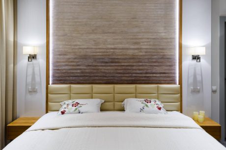 Stylish, minimalist bedroom with warm wooden wall panels, plush bedding, and modern lighting.