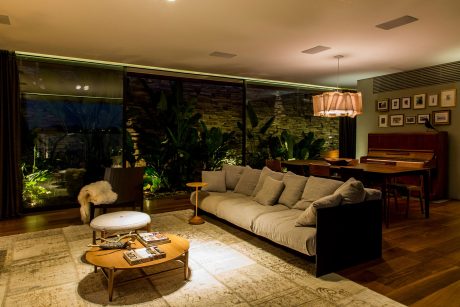 Cozy living space with rustic stone walls, plush sofa, and lush indoor plants creating a warm, inviting ambiance.