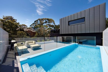 Modern architecture with sleek black exterior, glass walls, and a stunning pool.