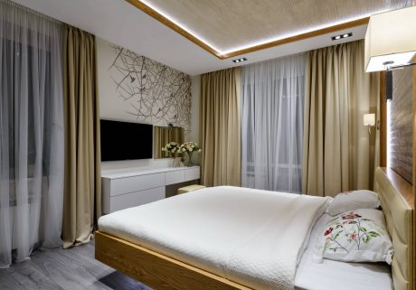 Luxurious bedroom with modern lighting, textured wall, and neutral curtains.