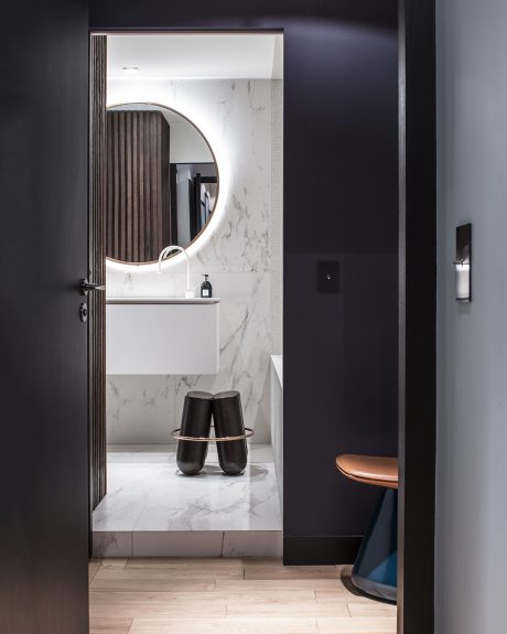 A sleek, modern bathroom with a round mirror, marble vanity, and minimalist decor.