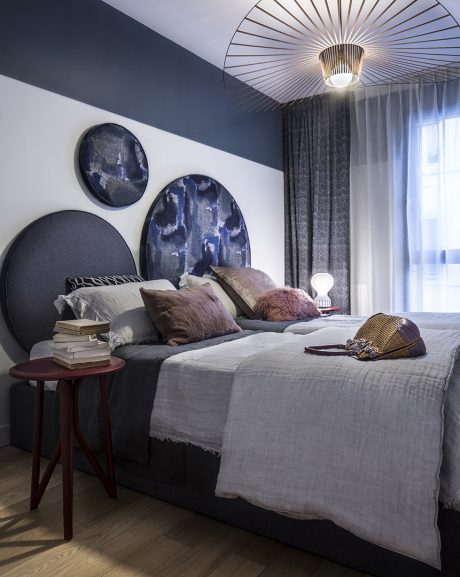 Sophisticated bedroom with artistic wall decor, plush bedding, and modern lighting.