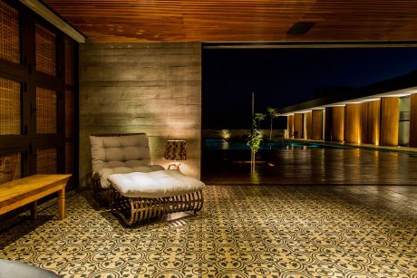 Inviting outdoor lounge area with patterned tiles, wooden walls, and a pool visible.