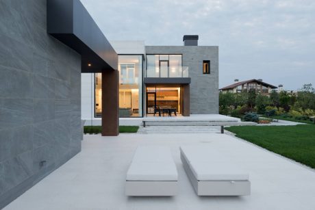 Modern, minimalist home with sleek concrete facade, large windows, and lush garden landscaping.