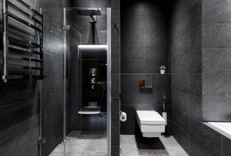 Dark and sleek modern bathroom with minimalist design, glass shower enclosure, and built-in shelving.