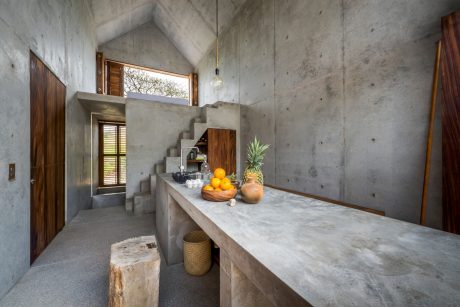 Concrete interior with wooden accents, geometric stairs, and a marble countertop.