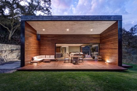 Stunning modern outdoor living space with warm wood accents, large deck, and stone walls.