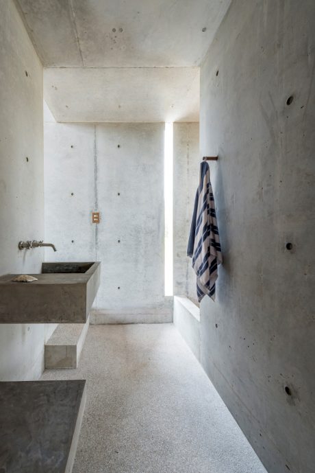 Minimalist concrete bathroom with a towel hanging on the wall and a concrete sink.