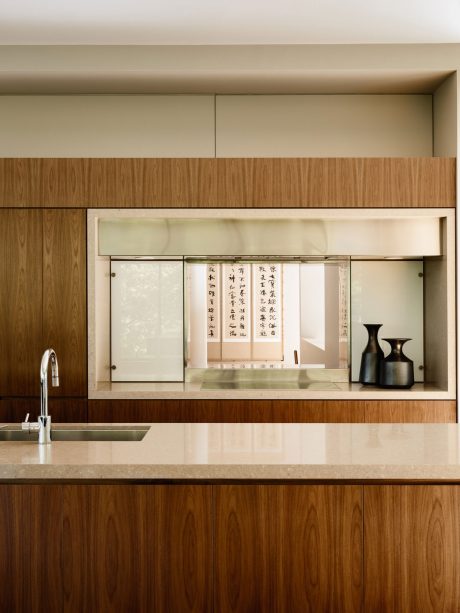 A modern kitchen design featuring wood paneling, minimalist shelving, and Asian-inspired decor.