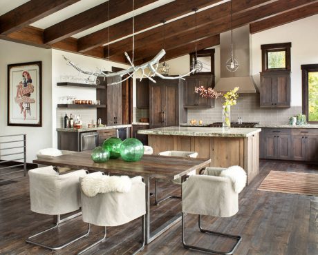 A rustic kitchen with exposed wooden beams and custom cabinetry, a stylish light fixture, and a cozy dining area.