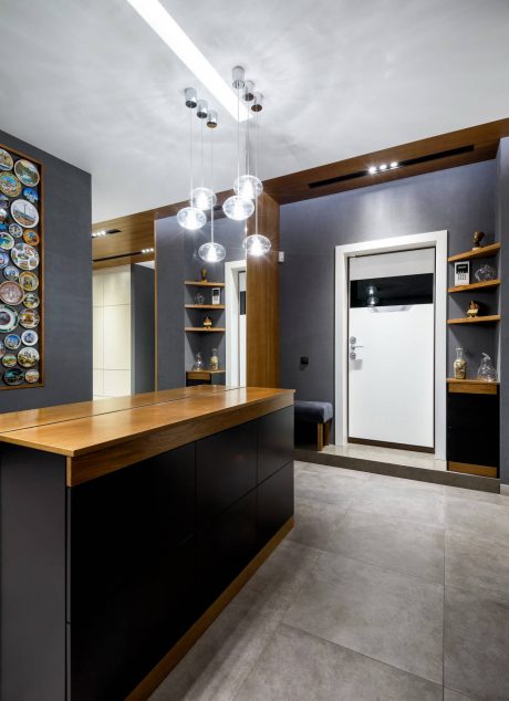 Modern kitchen with sleek black cabinetry, wooden countertops, and pendant lighting.