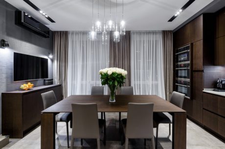 Sleek, modern dining area with statement chandelier, wooden table, and glass window treatments.