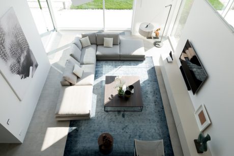 Spacious, modern living room with large gray sectional, coffee table, and views of the outdoors.